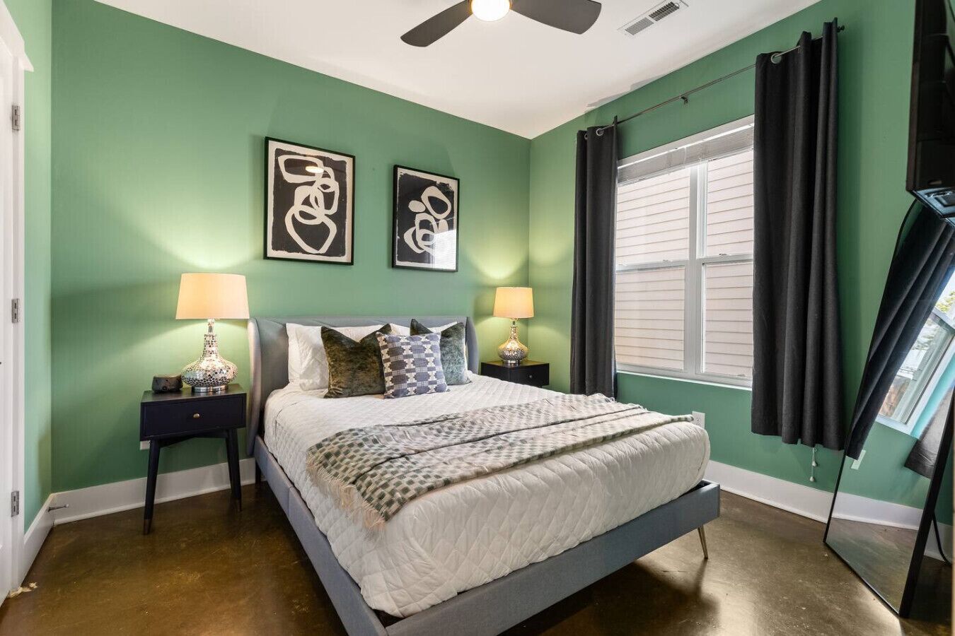 A bedroom with a bed, two nightstands, a ceiling fan, and a window with curtains.