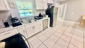 A modern kitchen with white cabinets, a stainless steel refrigerator, and a window with a view of the outside.
