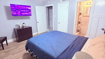 A bedroom with a bed, a TV, a ceiling fan, and a bathroom door.