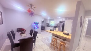 A modern kitchen with a central island, a dining area with a table and chairs, and a ceiling fan.