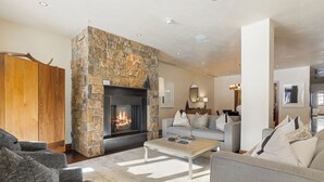 A modern living room with a stone fireplace, grey sofas, and a wooden wardrobe. - Spacious and Elegant Residence in Solaris Vail with Stunning Mountain Views; 4AE (Vail)