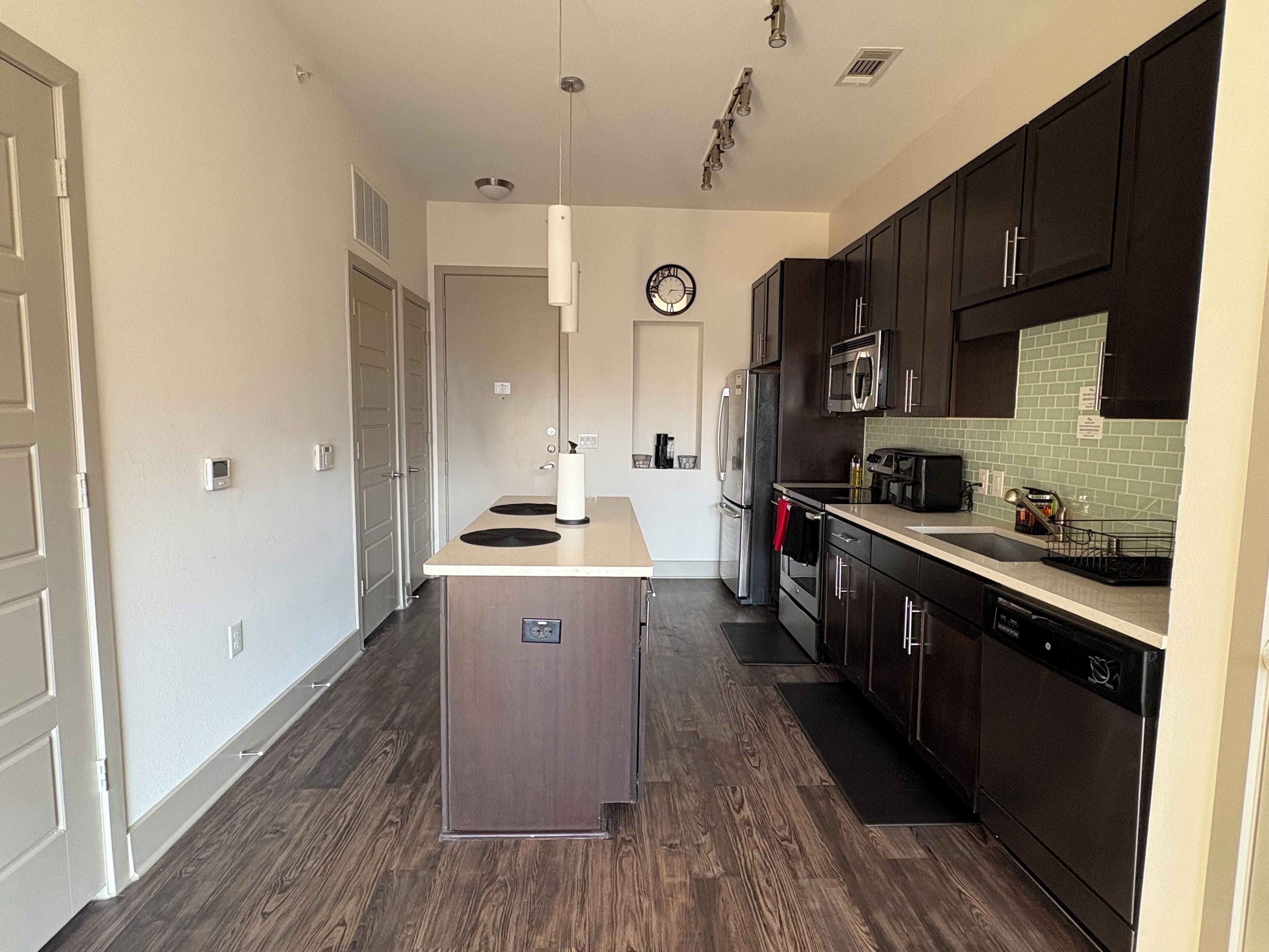 A modern kitchen with dark wood cabinets, stainless steel appliances, and a central island.