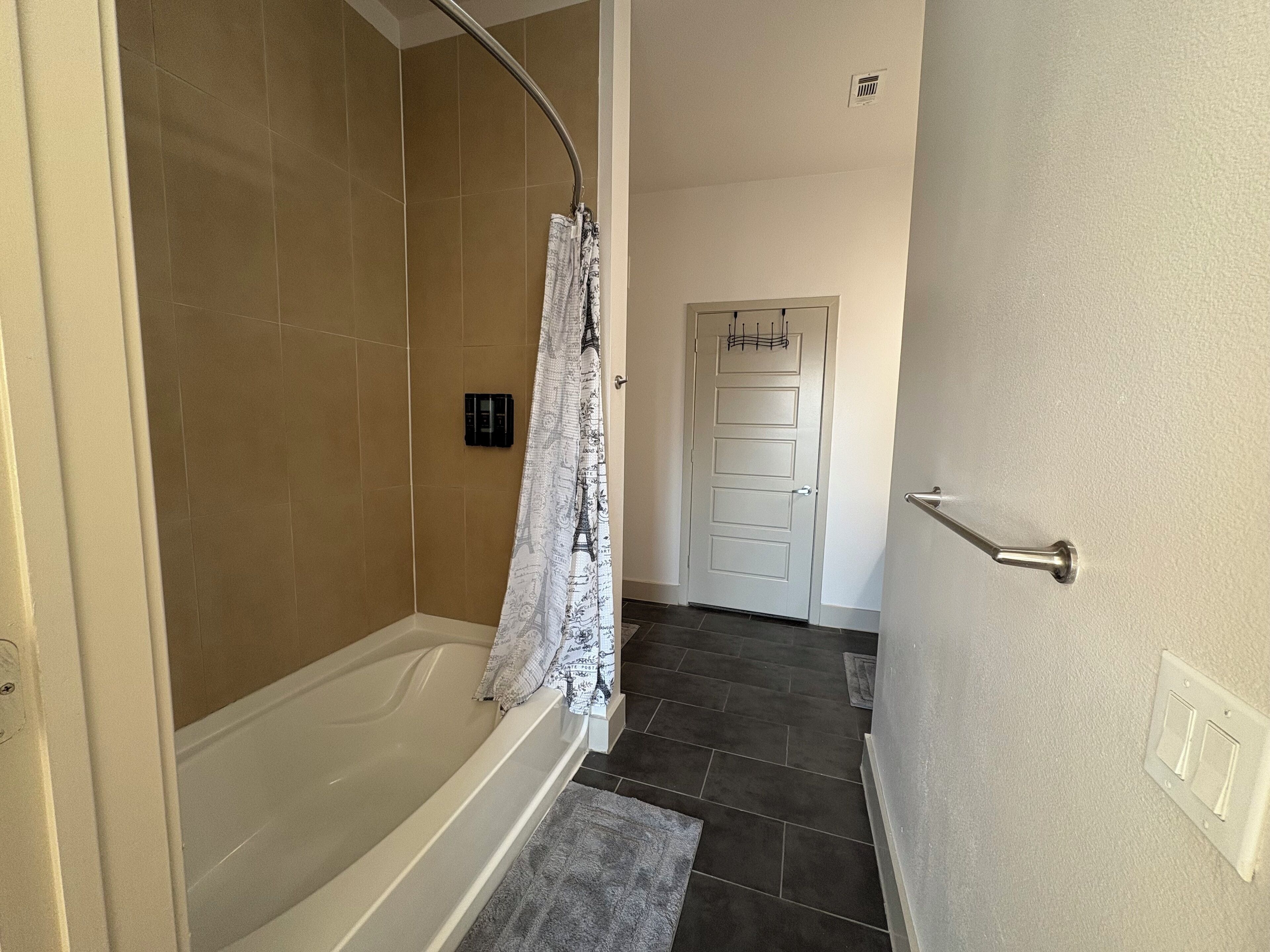 A bathroom with a bathtub, shower, and a door with a towel rack.