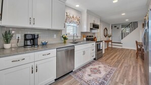 A modern kitchen with white cabinets, stainless steel appliances, and a wooden floor. - Cozy Farmhouse, Hot tub and Sauna on 8 acres! (Troutville)