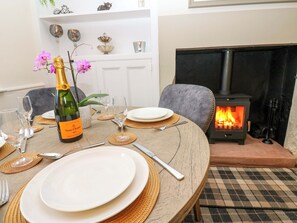 A dining table set with plates, cutlery, and a bottle of champagne. A fireplace is visible in the background. - Milford (Carlisle)