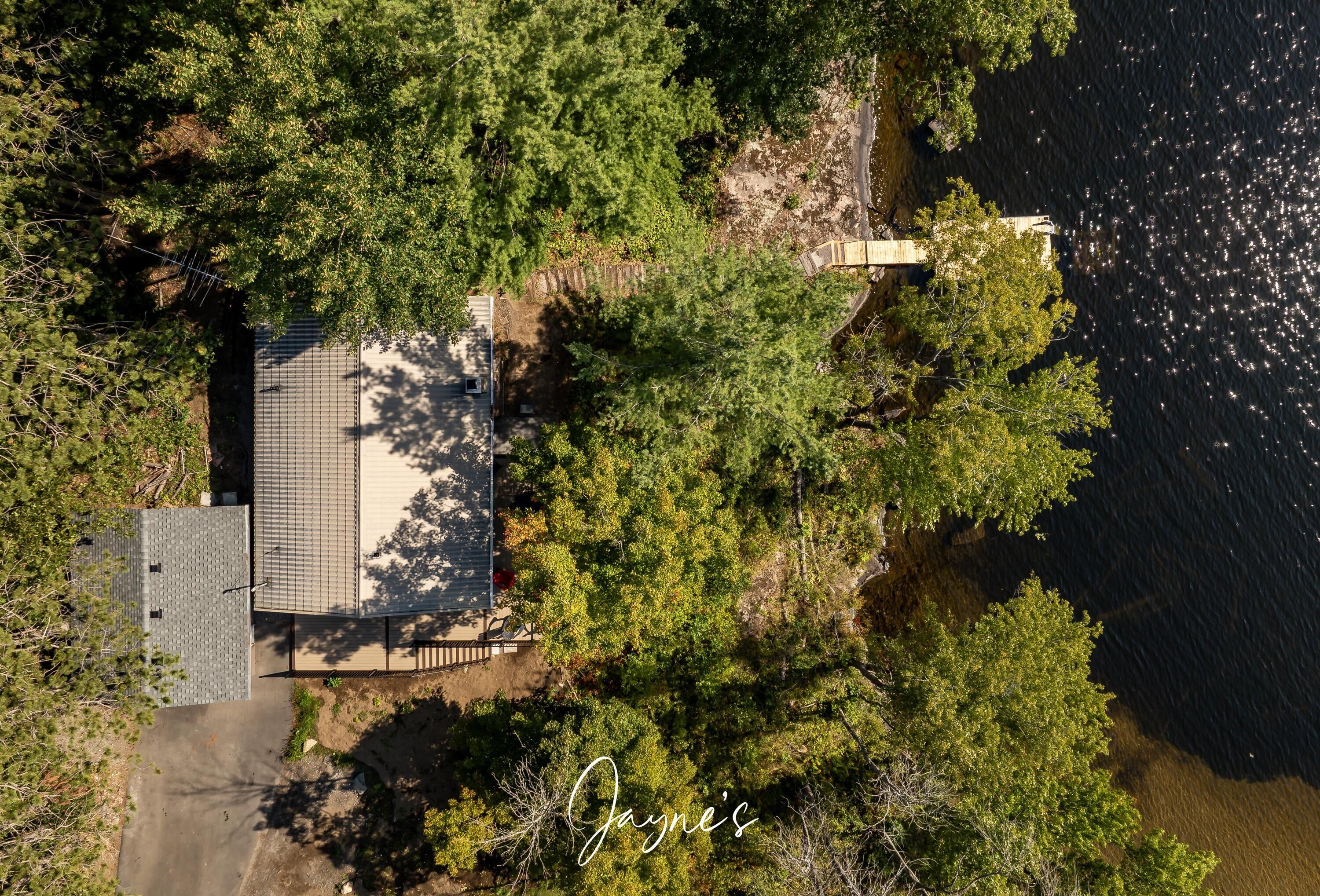 An aerial view of a property with a house, a fenced yard, and a body of water.