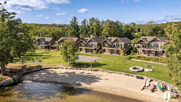 A lodge with multiple cabins, a sandy beach, and a small water body.