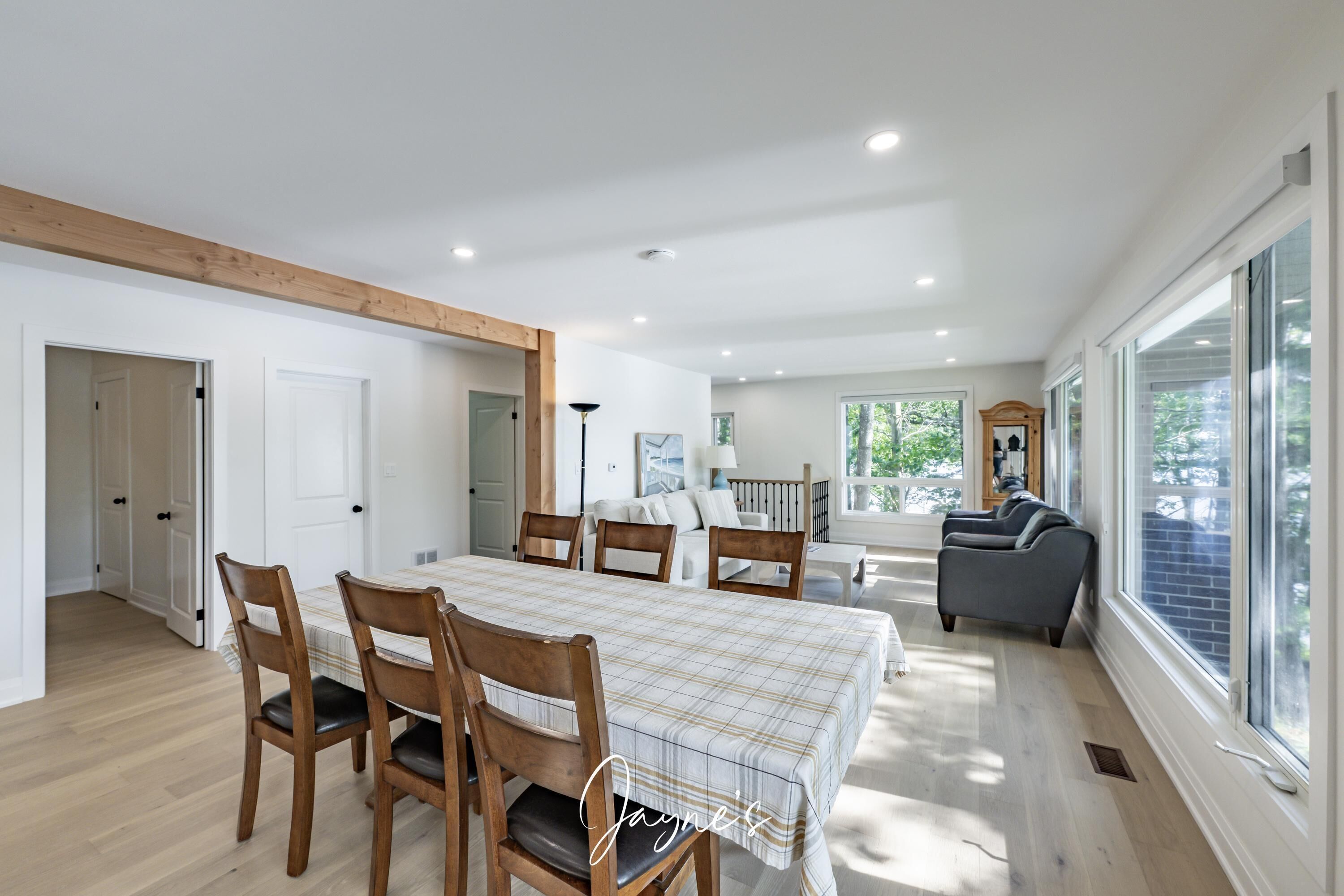A spacious living room with a dining area, large windows, and a view of the outdoors.