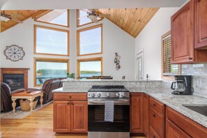A kitchen with a large island, wooden cabinets, and a view of a lake.