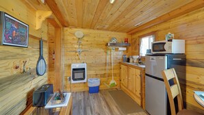 L’intérieur d’une cabane en bois comprend un coin cuisine, un espace repas et un ventilateur de plafond.