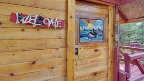 Une cabane en bois avec une pancarte « Bienvenue » et une peinture représentant un ours.