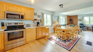 A kitchen with wooden cabinets, stainless steel appliances, and a dining area with a table and chairs. - Mtn Views, On-Site Trails! Spacious Bartlett Home (Bartlett)