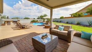 Un patio couvert avec des meubles d’extérieur, une piscine et une vue sur le jardin arrière.