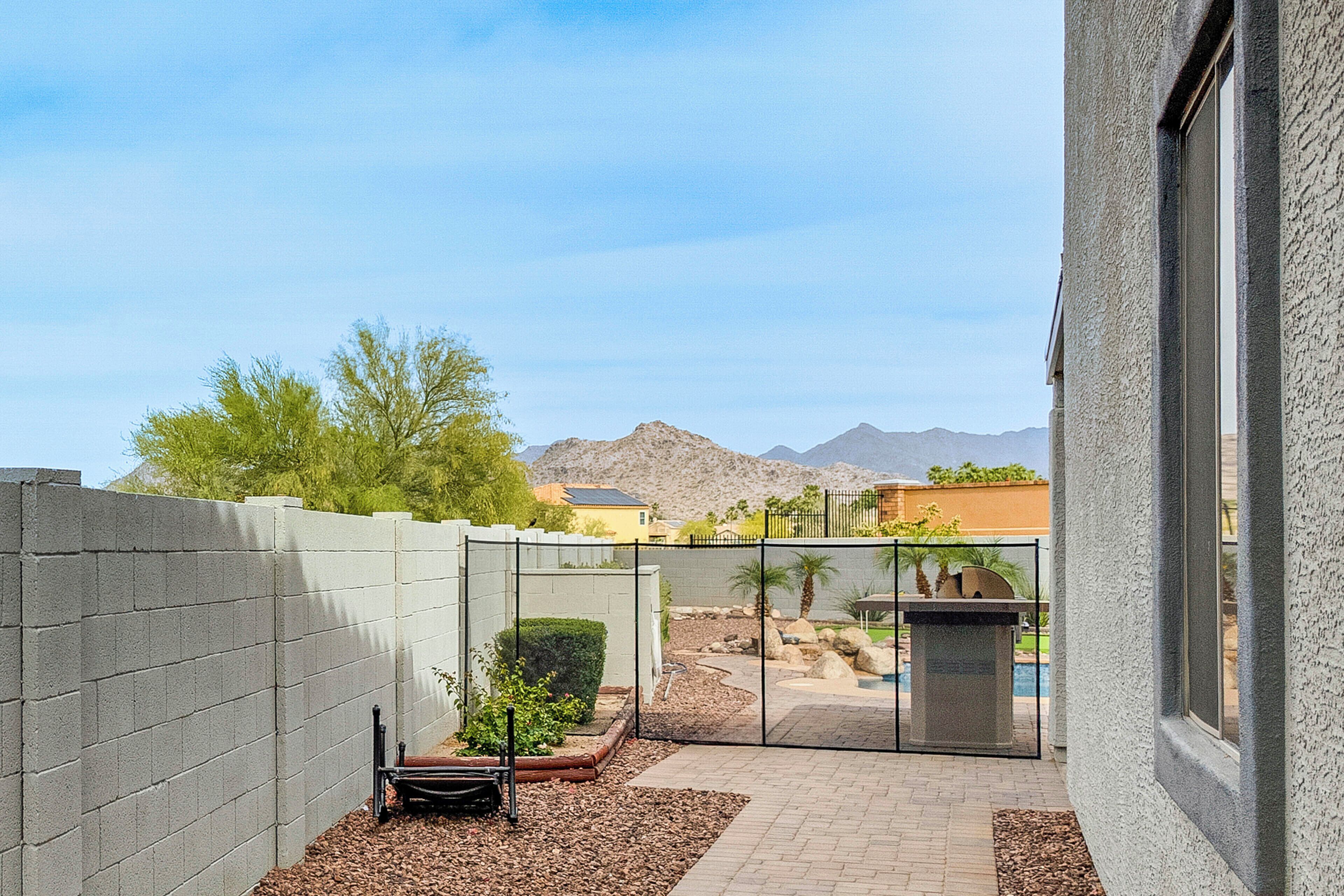 A courtyard with a pool, a white wall, and a mountain view.