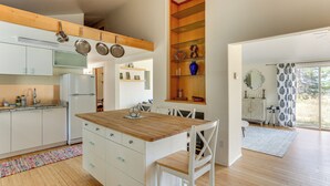 A modern kitchen with white cabinets, a wooden island, and hanging pots. - Outdoor Adventure Haven - 15 Mi to Mount Shasta! (Weed)
