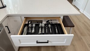 A kitchen with a white countertop, a drawer organizer with utensils, and a wooden floor. - New Home in Urbandale/Des Moines – Modern Comfort In Prime Location! (Urbandale)