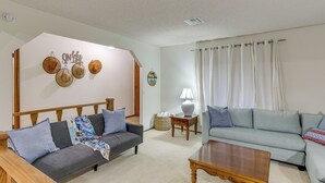 Ein Wohnzimmer mit grauem Sofa, blauem Sofa, Couchtisch aus Holz und einer Lampe auf einem Beistelltisch.