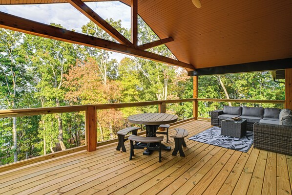 Une terrasse en bois avec une table et des bancs, donnant sur une zone boisée.