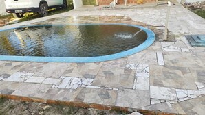 A swimming pool with a blue edge, surrounded by a stone-tiled deck. - Cozy beach house with pool, in Aver o Mar, year-round sunshine. (Barra do Sirinhaém)