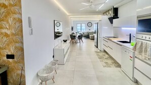 Eine moderne Küche mit weißen Schränken, einem eingebauten Backofen und einer Essecke mit Tisch und Stühlen.