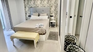 Ein modernes Schlafzimmer mit einem großen Bett, Nachttischen, einer Bank und einer Wand mit Muster.