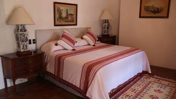 A neatly arranged bedroom with a bed, two bedside tables, two lamps, and two framed pictures on the wall.