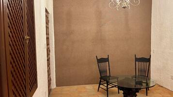 Un comedor con una mesa de vidrio rodeada de sillas, una pared marrón y un techo con textura.