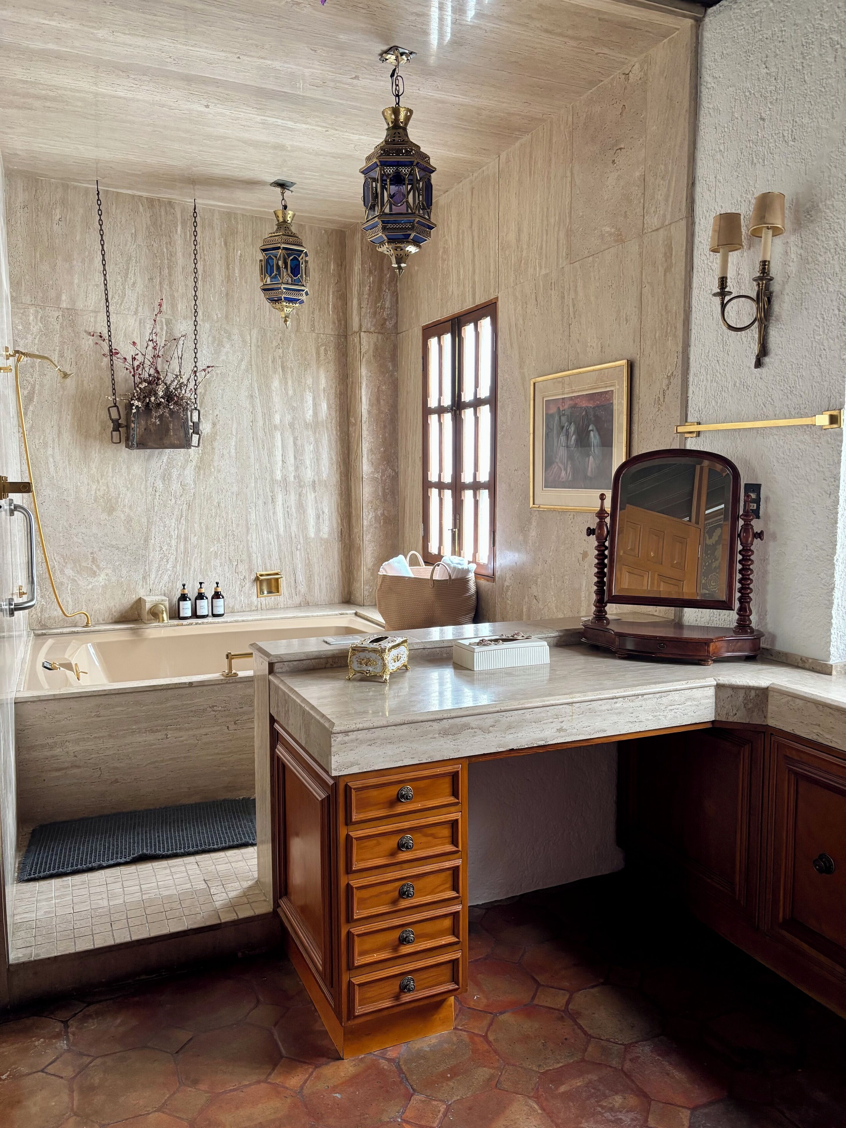 Un baño con bañera, lavamanos, tocador con cajones, espejo y lámpara colgante.