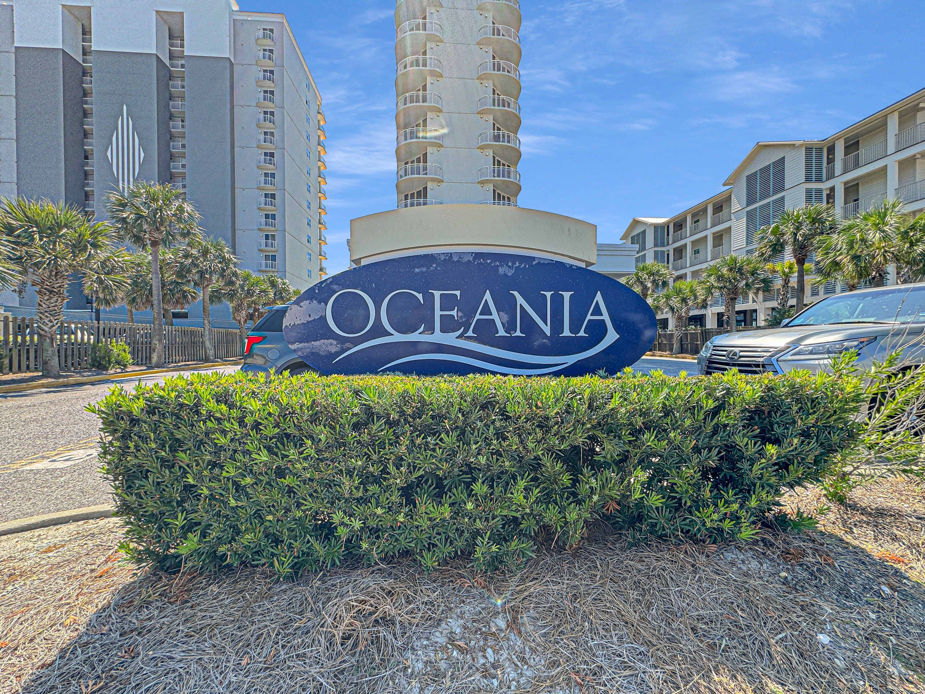Ein Schild für das Hotel OCEANIA mit einem modernen Gebäude im Hintergrund.