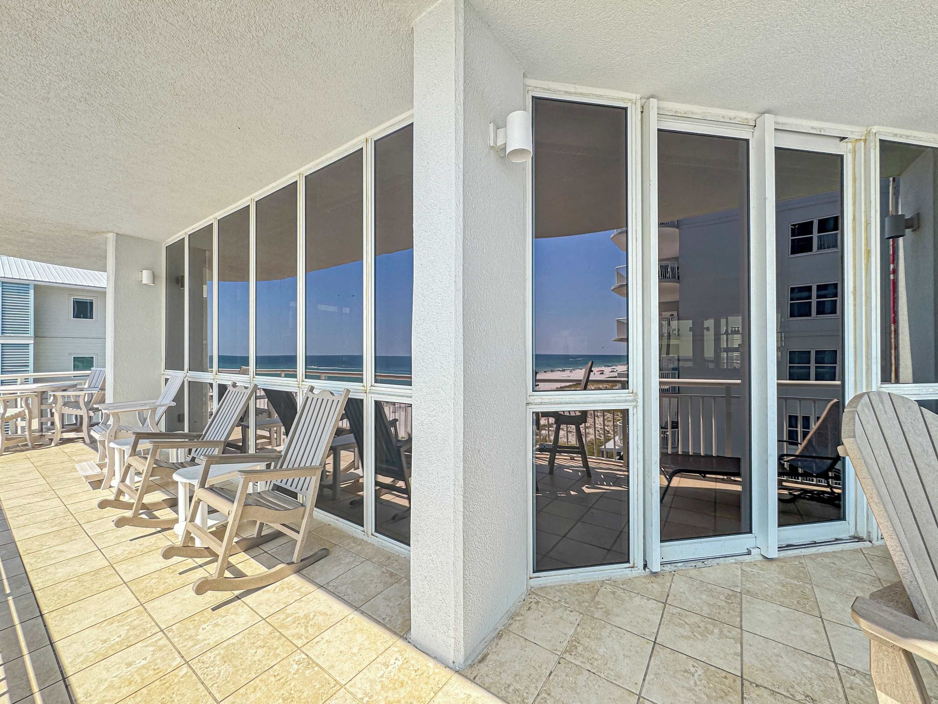 Un espace extérieur abrité, doté de chaises et de tables, de grandes portes-fenêtres coulissantes et offrant une vue sur la plage.