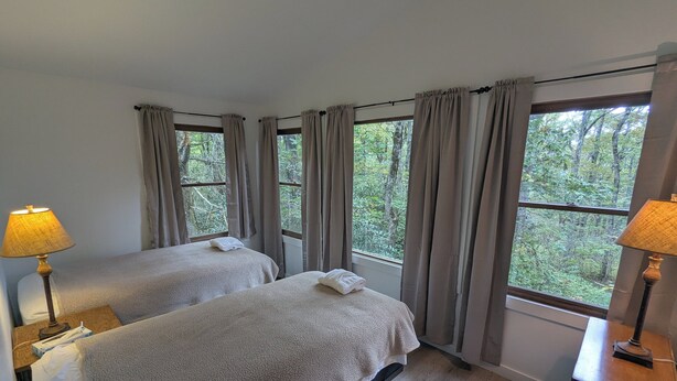 A room with two beds, a wooden dresser, and a window with curtains.
