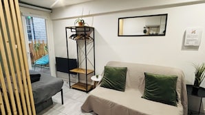 Ein modernes Wohnzimmer mit einer Couch, einem kleinen Tisch, einer hängenden Pflanze und einem Spiegel an der Wand.