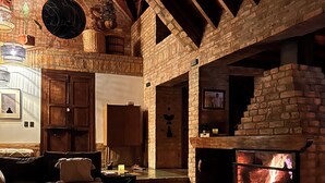 Um interior acolhedor com lareira, vigas de madeira e parede de pedra.
