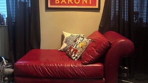 Ein rotes Ledersofa mit Zierkissen, ein gerahmtes Poster an der Wand und ein gemustertes Teppich.