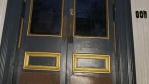 Eine schwarze Tür mit goldener Verzierung und einer Messingklinke.
