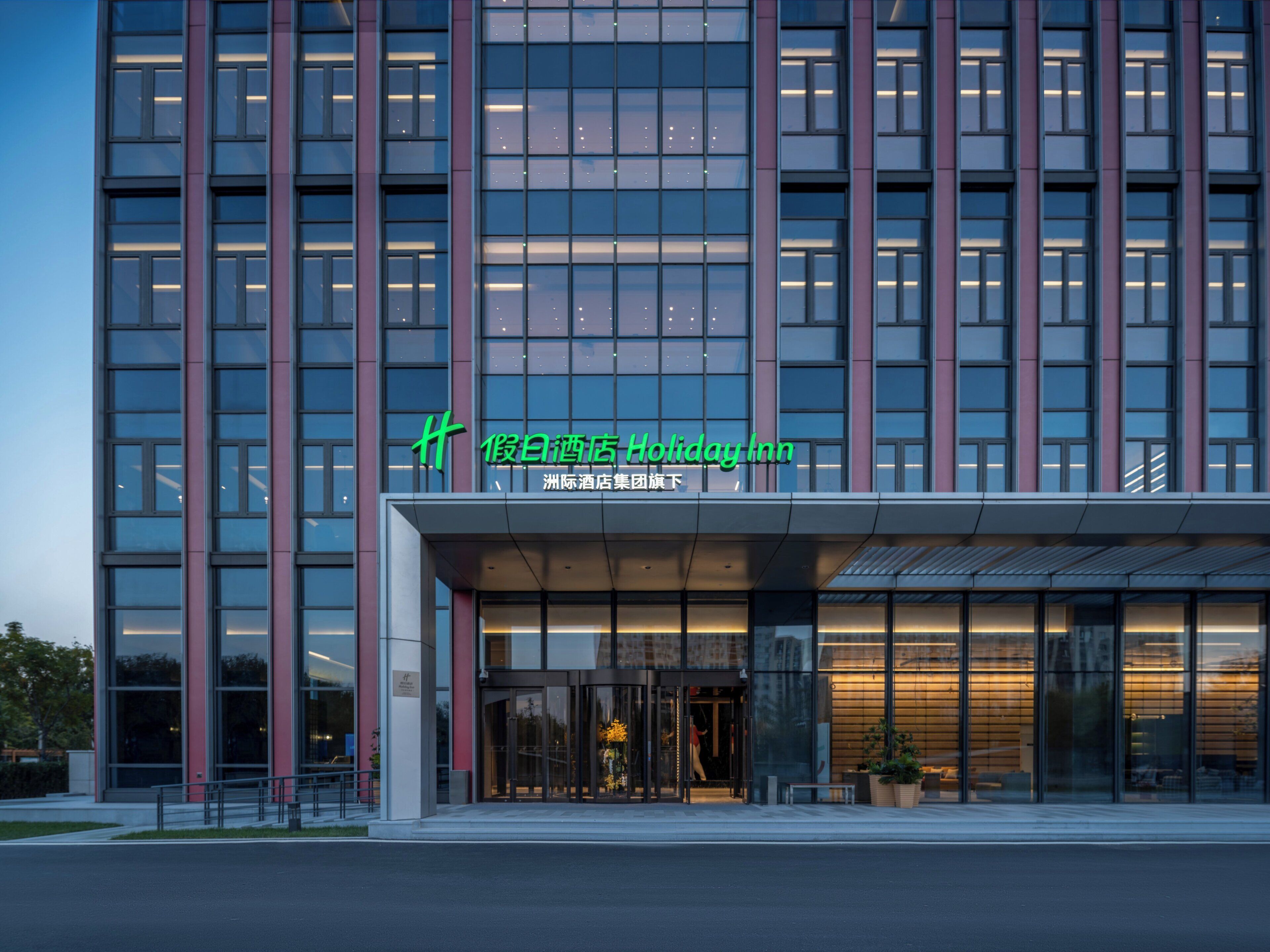 A modern hotel building with a glass facade, a prominent signage, and a well-lit entrance.