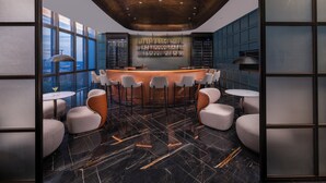 Un espace bar moderne doté d’un plafond incurvé, de tabourets de bar et d’un présentoir à vin.