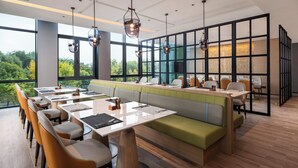 Un restaurant moderne doté d’une grande table conviviale, de cabines individuelles et offrant une vue sur l’extérieur.