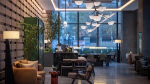 Un intérieur moderne comprenant un espace salon, un comptoir d’accueil et de grandes fenêtres.