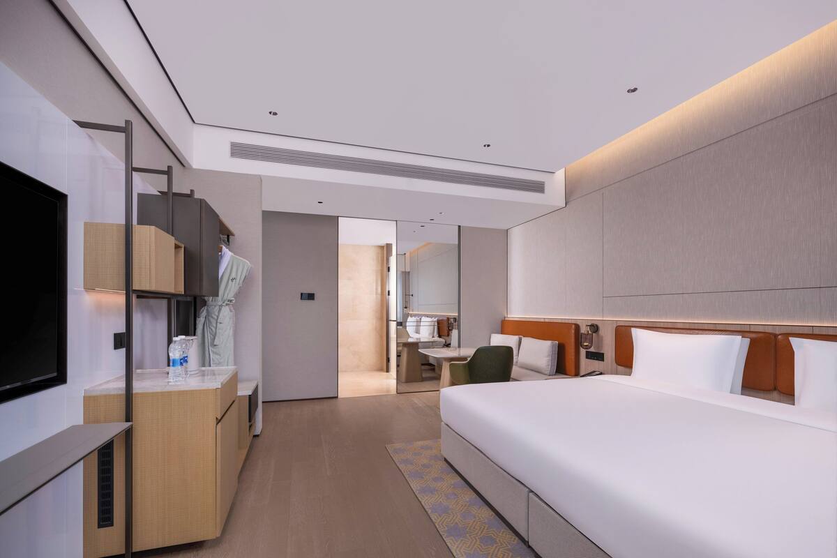 A modern hotel room with a large bed, a desk, and a television.