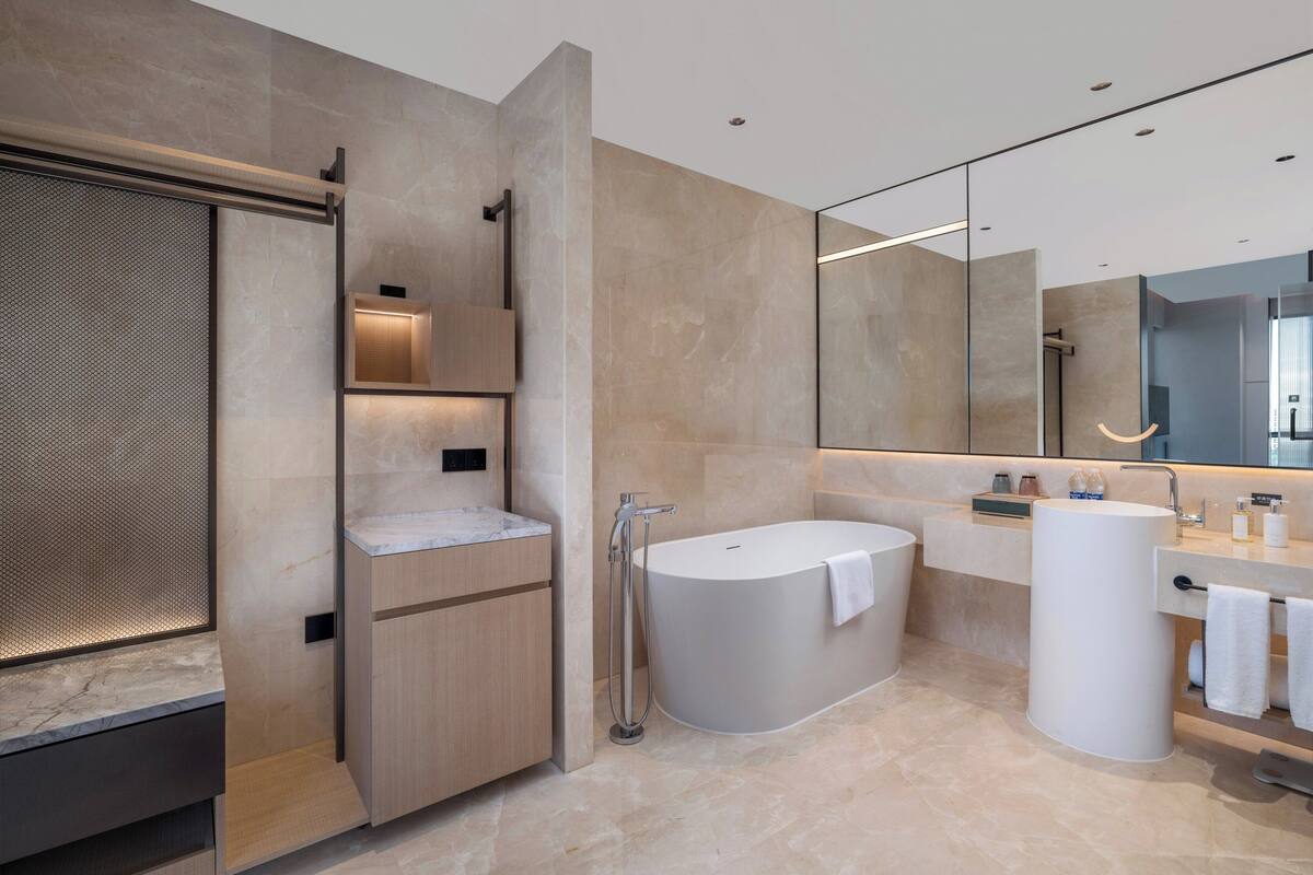 A modern bathroom with a freestanding bathtub, a large mirror, and a vanity with a sink and towel rack.