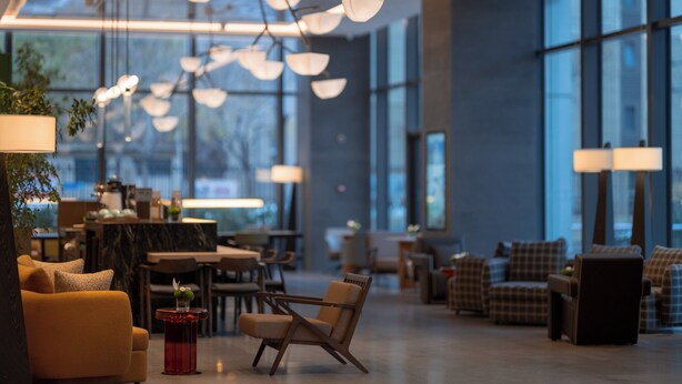 Un intérieur moderne comprenant différents espaces de détente, avec des canapés et des fauteuils, ainsi qu’un coin repas avec des tables.