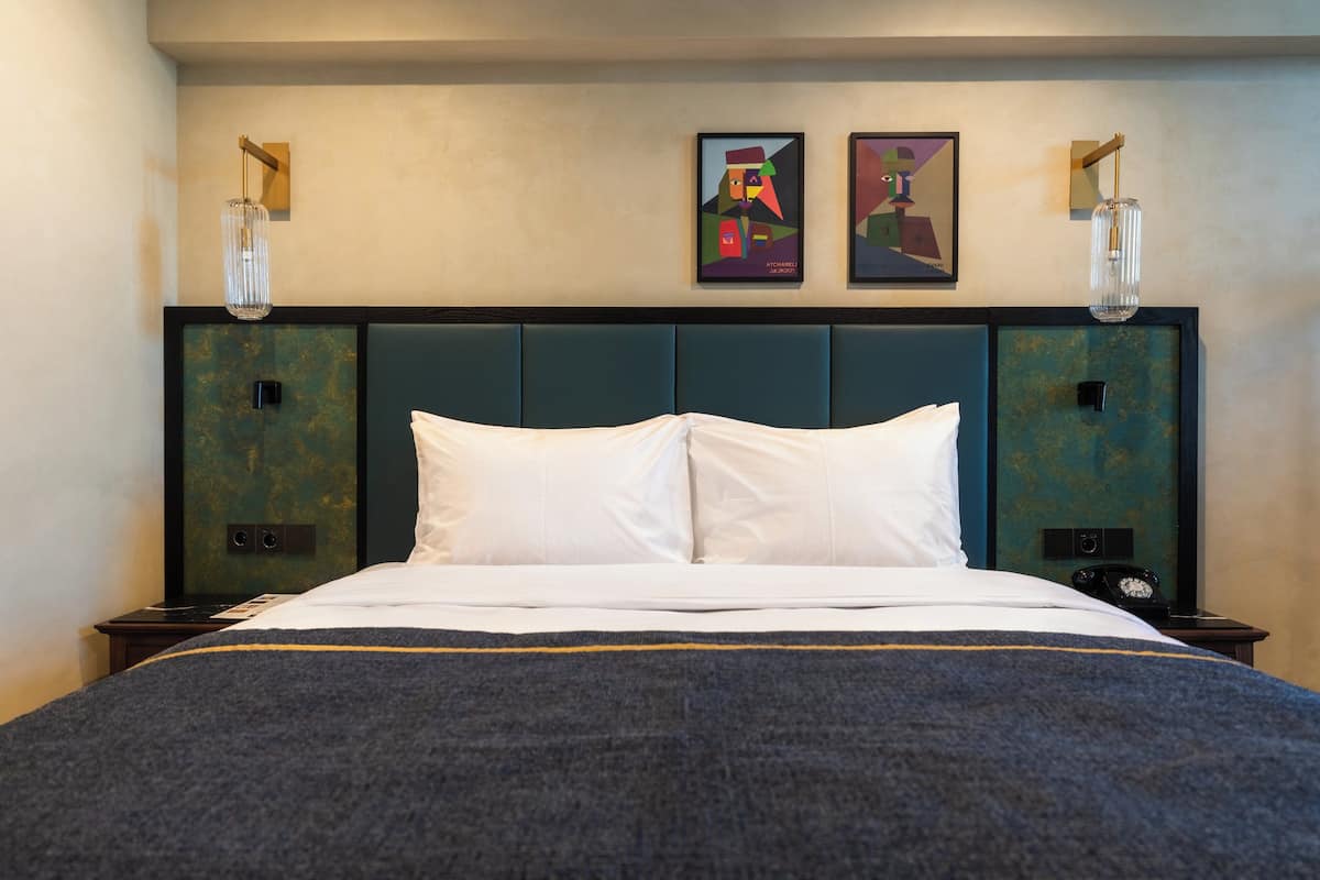 Ein Hotelzimmer mit einem großen Bett, zwei Wandleuchten und zwei gerahmten Kunstwerken darüber.