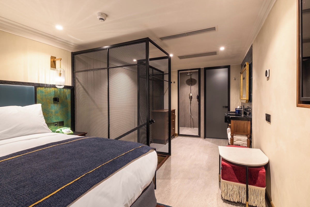Ein Hotelzimmer mit Bett, Schreibtisch, Duschbereich und Badezimmer.