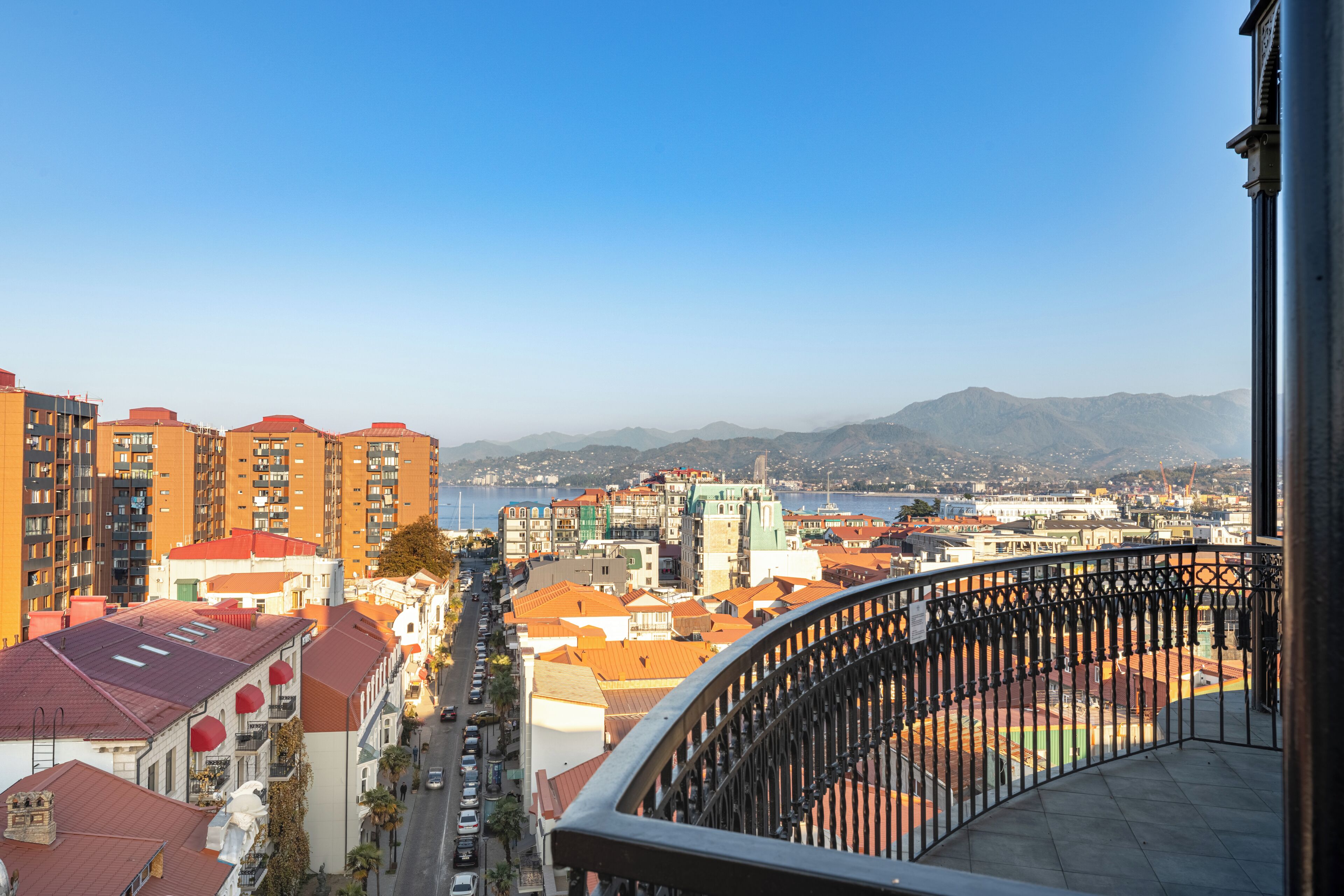 A high-rise building with balconies overlooking a cityscape and a body of water.