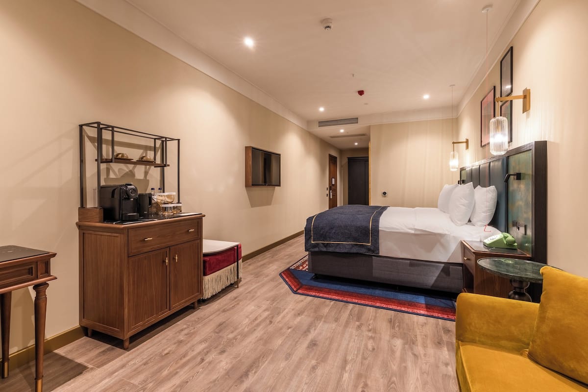 Ein Hotelzimmer mit einem Bett, einem Schreibtisch, einem Kleiderschrank, einem Fernseher und einem kleinen Tisch.