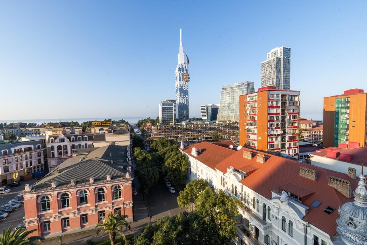 Eine Stadtansicht mit einem markanten Turm, verschiedenen Gebäuden und einer Mischung aus Baustilen.