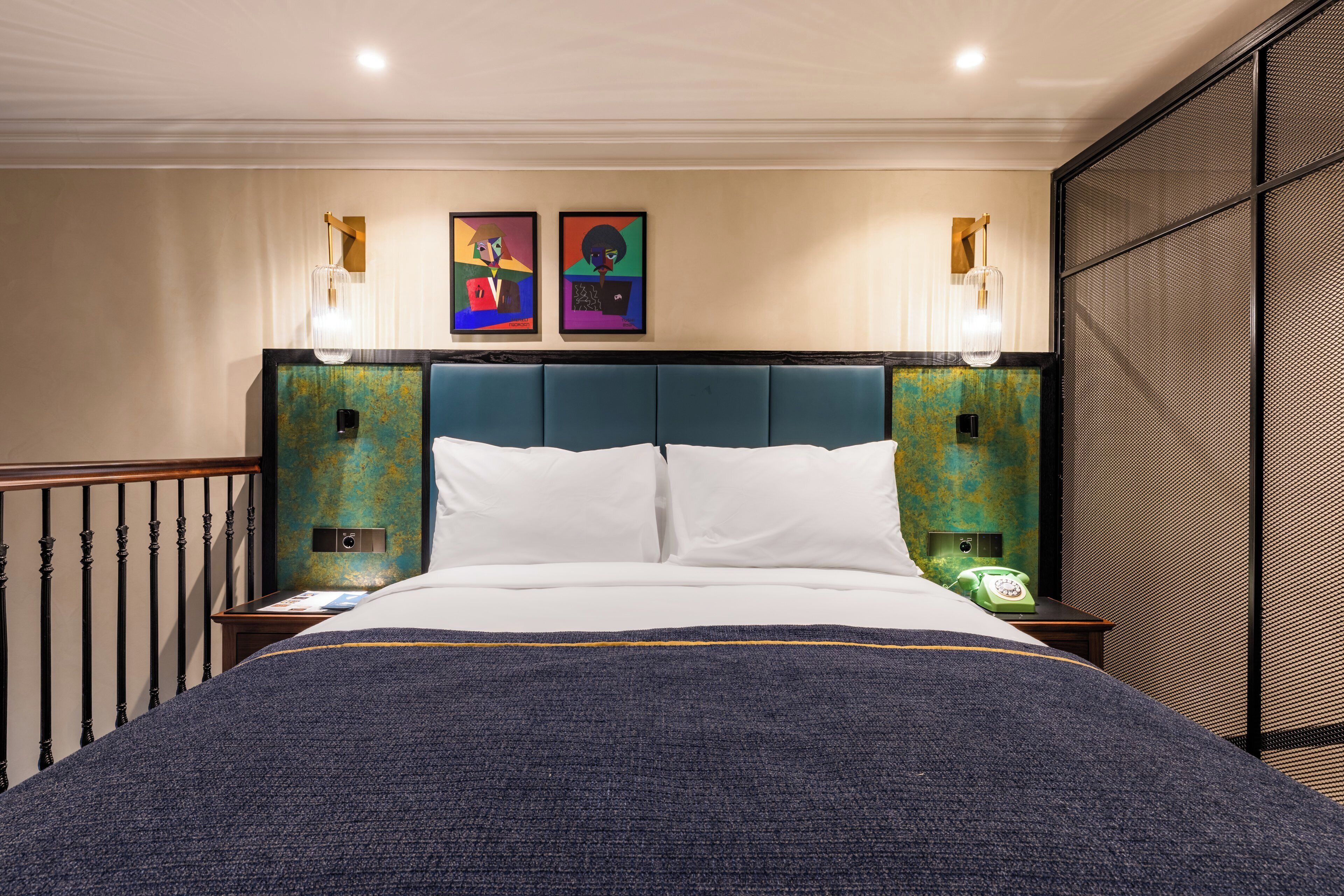 Habitación de hotel con una cama grande, dos lámparas de pared y dos cuadros enmarcados sobre la cama.
