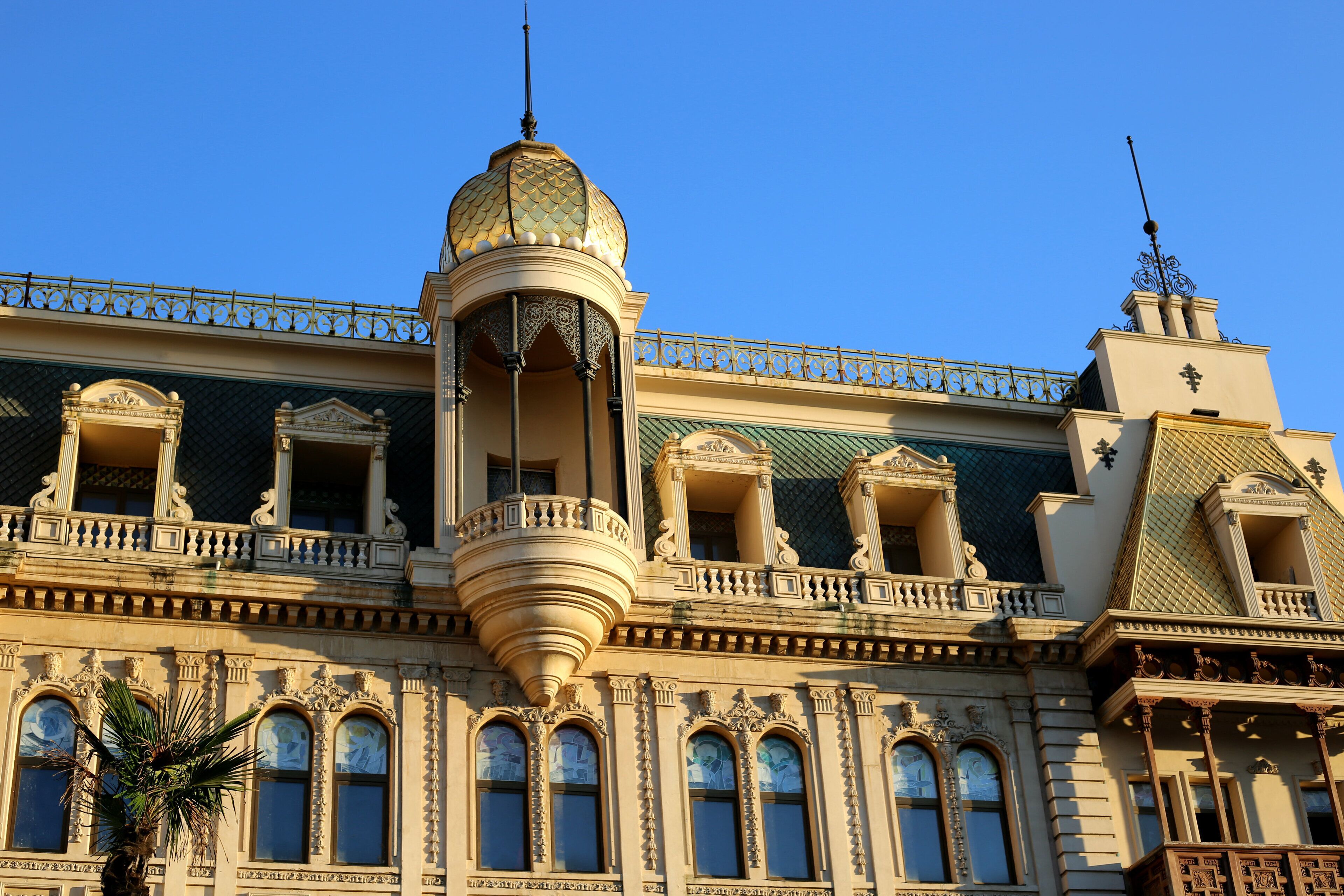 A historic building with ornate balconies, a central dome, and a decorative fence.