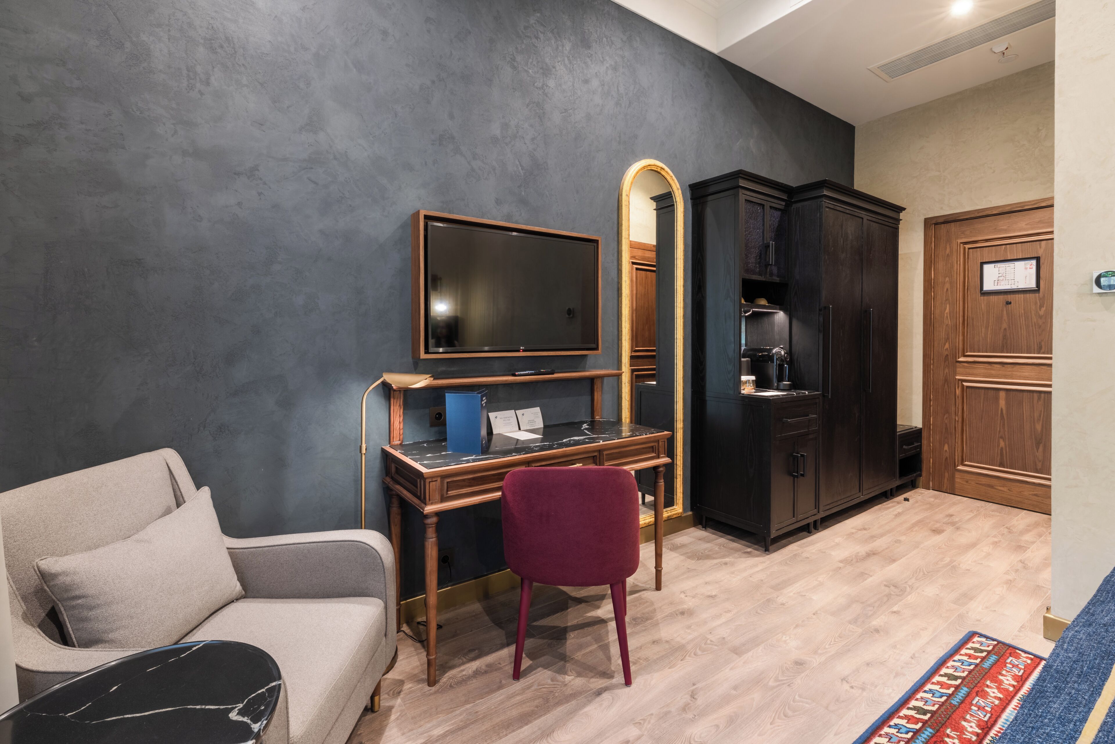 A room with a sofa, a desk with a TV, a mirror, and a wardrobe.